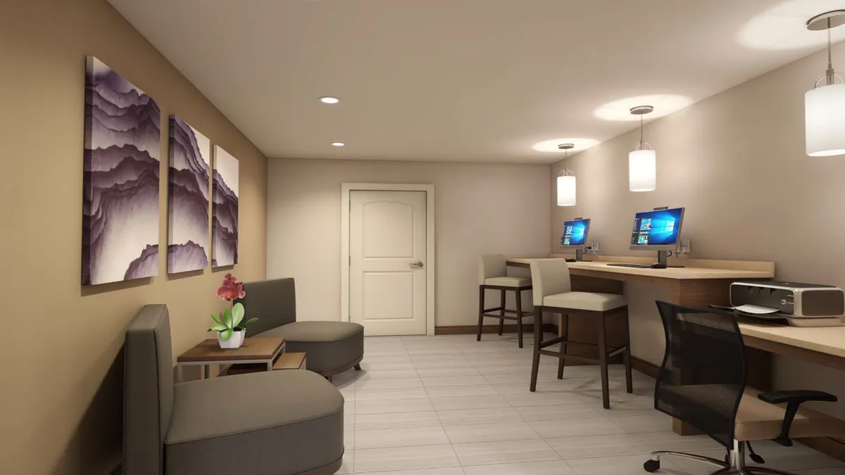 A modern, well-appointed communal workspace with computers, abstract artwork, and comfortable seating areas with small tables, ideal for focused work or creative thinking.