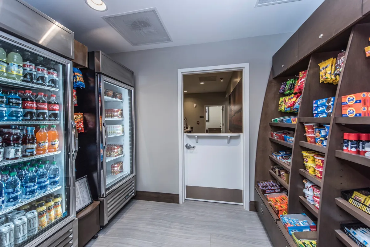 This image displays the entrance area featuring a refrigerated drink display and neatly organized snack shelves. The convenient setup suggests easy access for guests looking to grab a quick refreshment or snack, with a casual, welcoming vibe ideal for those coming and going during their explorations.